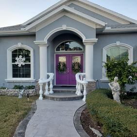 Professional exterior stucco house painting on a unique rotunda-style home with a custom purple front door in Englewood, Florida by Best Paint Lines.