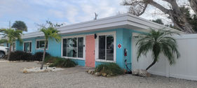 Freshly painted bright blue beach apartment building with custom coral doors on Minnesota Beach Road in Englewood FL by Best Paint Lines.