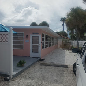 Fully repainted beach house exterior showing immaculate wood siding, a stained deck, and crisp window frames in Englewood, Florida by Best Paint Lines.