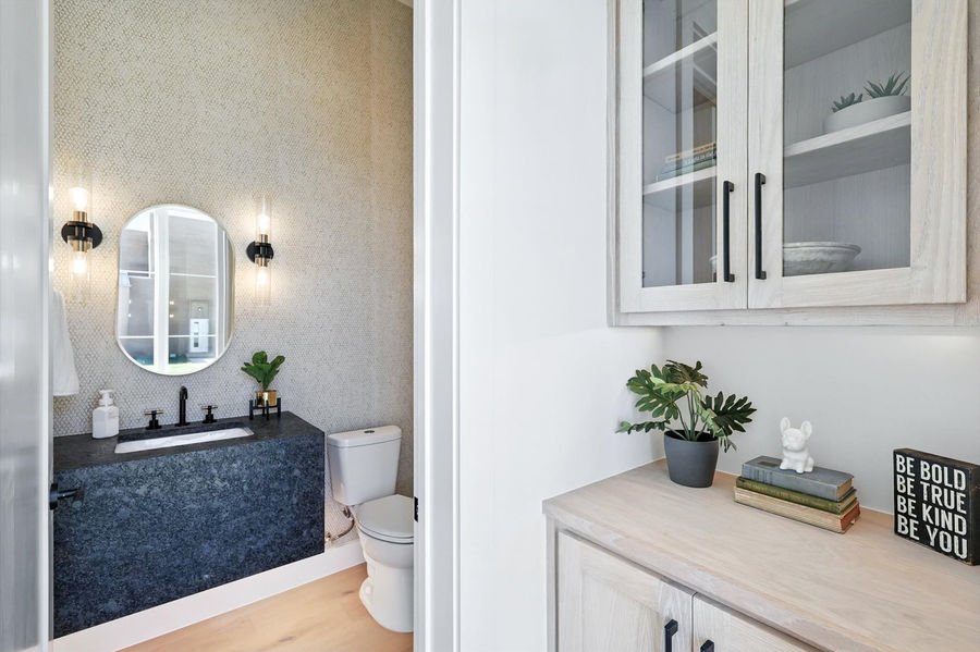 Modern powder room at 200 N Pine St, Roanoke, TX, with a floating vanity, dark countertop, and gold and black light fixtures, showcasing a stylish and high-end design