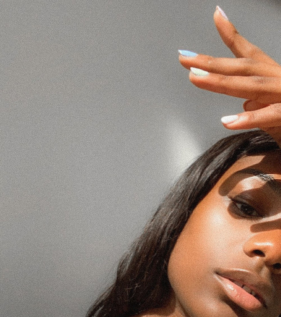 Tosin Odugbemi posing with her hand above her head and half her face off camera.