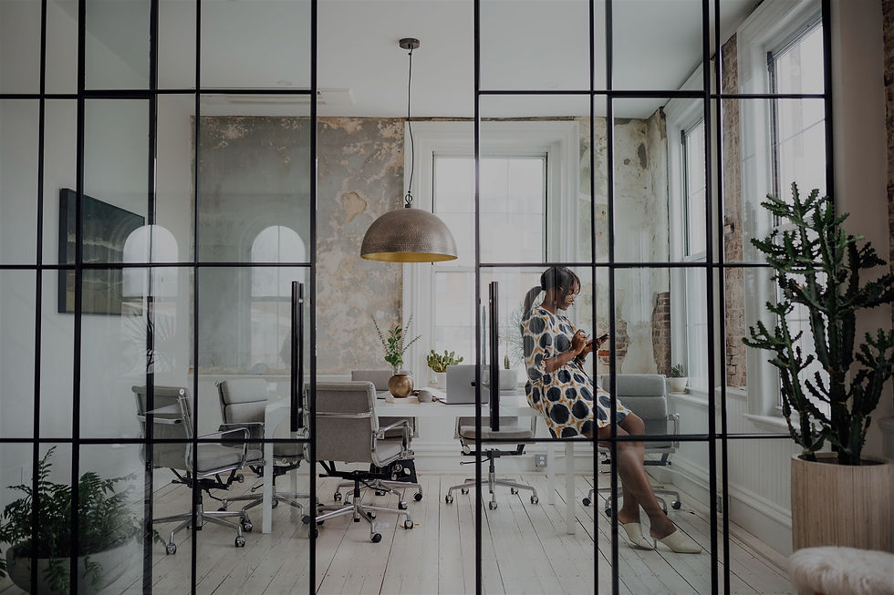 Digital marketing agency in Toronto workspace with glass-partitioned meeting room, natural light, and a woman, Tosin Odugbemi Hoskins, working on her iPhone in a refined, minimalist office.