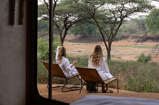 Ruaha Nationaal Park met twee vrouwelijke reizigers op hun terras in badjassen met uitzicht op de rivierbedding