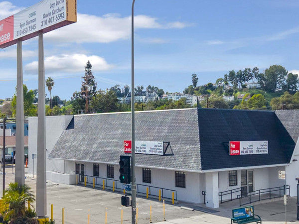 Light-colored commercial building with black roof and tall pylon sign showing the exterior of 21108 ventura blvd