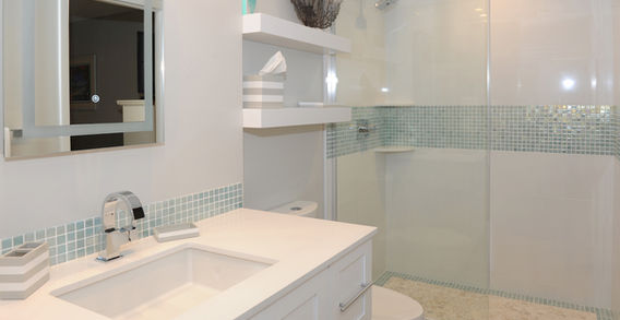 Guest bathroom with a spacious shower, back-lit mirror, open shelving, and modern floating cabinets.