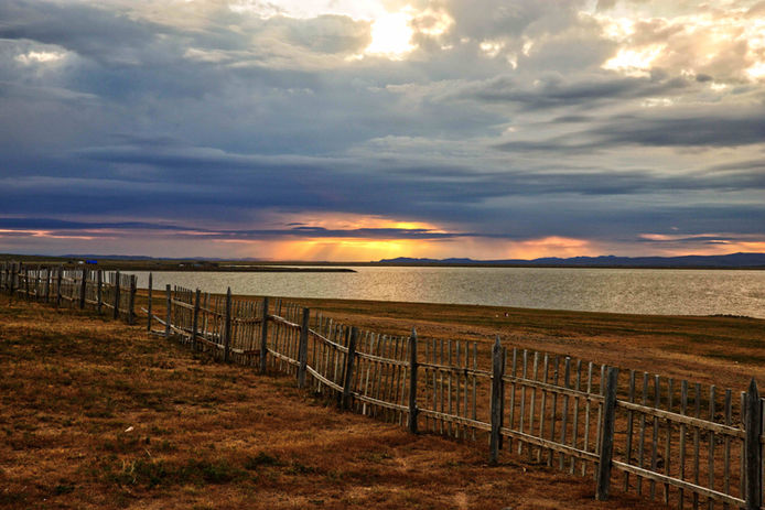 Die Sonne verschwindet dramatisch hinter einem mongolischen See.