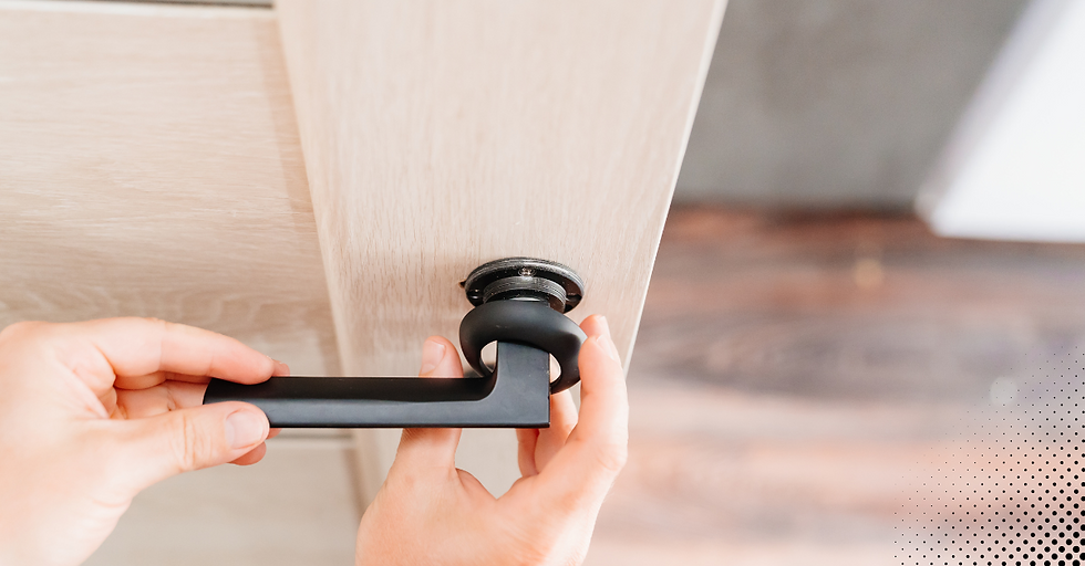 Installing a black door handle on a light wood door.