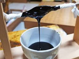 Laca urushi natural japonesa vertiéndose en un recipiente, utilizada para el Kintsugi tradicional y la restauración de cerámica.
