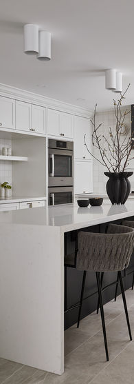 White waterfall kitchen island with charcoal base allows seating for four people.