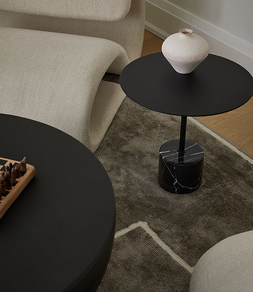 Sculptural upholstered lounge chair with two black coffee tables