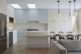 Landscape shot of a kitchen design with blue millwork, kitchen-dining integrated island and multiple globe pendants