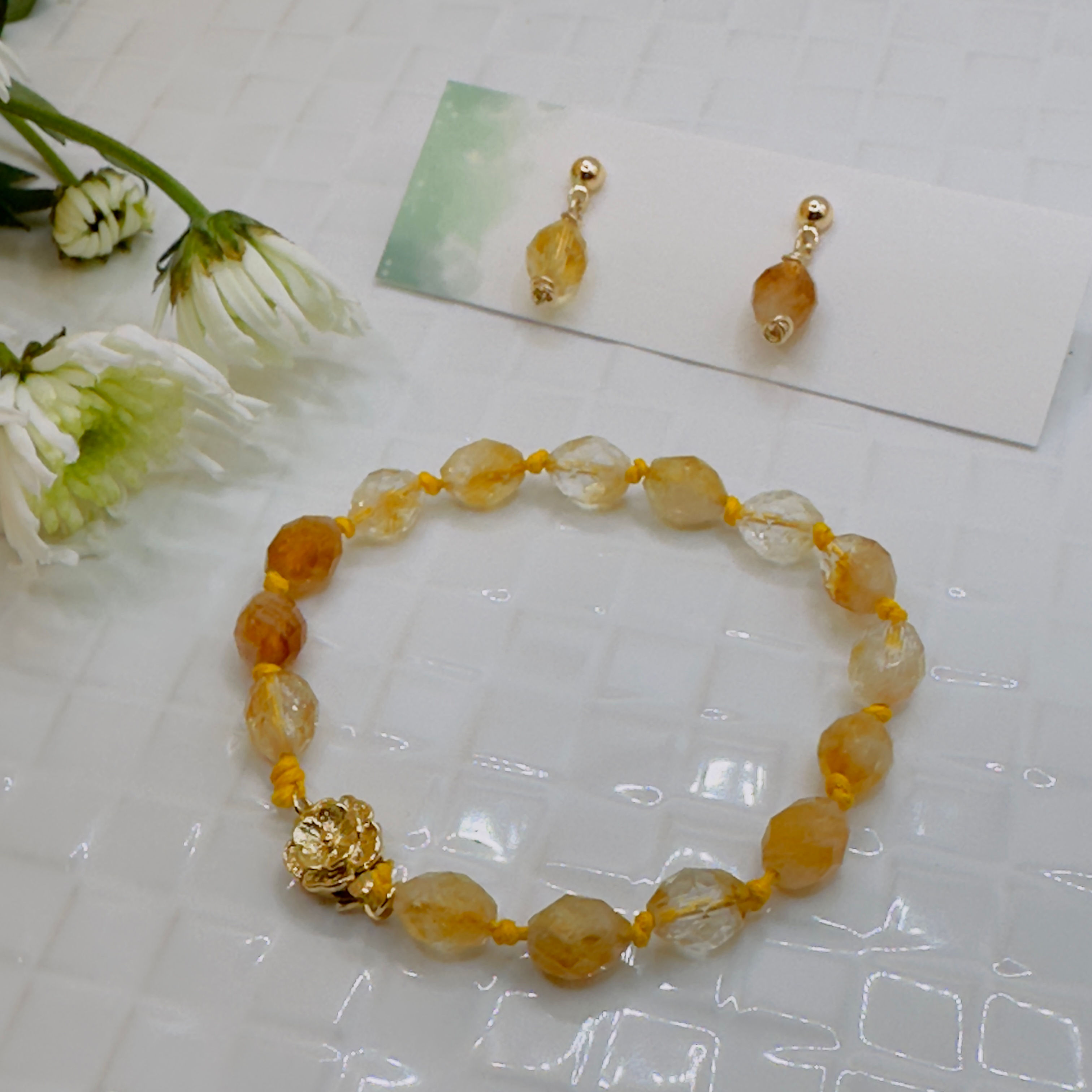 Yellow gemstone bracelet and earrings on white surface, fashion jewelry details