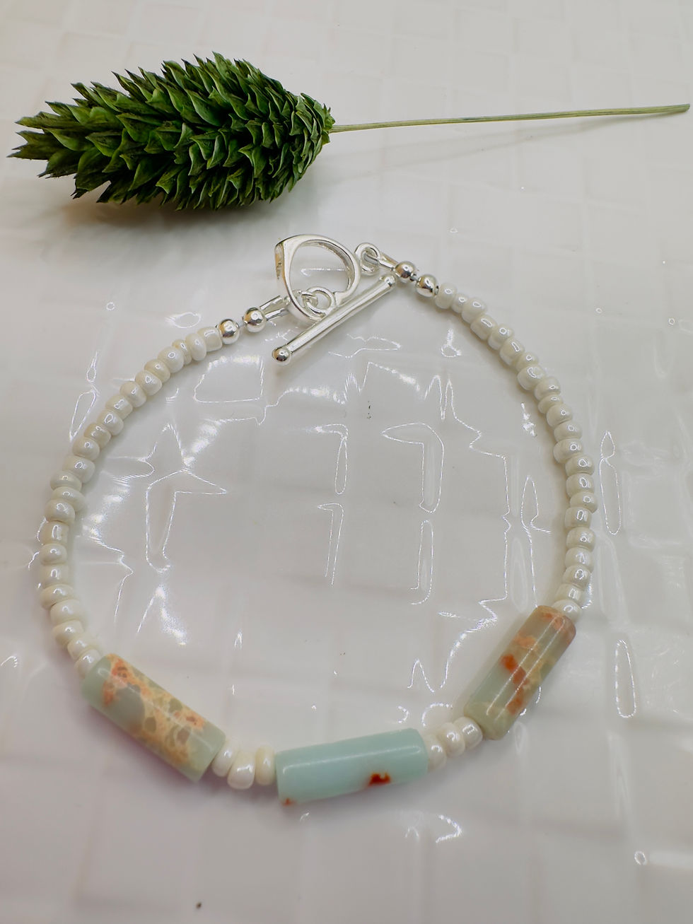 Delicate bracelet with white beads and unique stone accents, close-up shot.