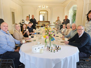 People sitting around a large table celebrating the launch of scented candles.