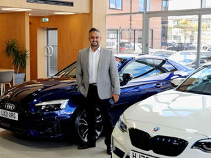 MD standing in the garage showroom, selling new cars.