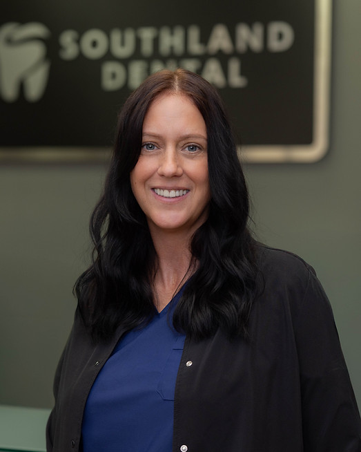 Smiling woman with long dark hair in blue scrubs, Southland Dental sign in background.