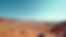 Wide angle view of rugged desert terrain with distant mountains under a clear blue sky