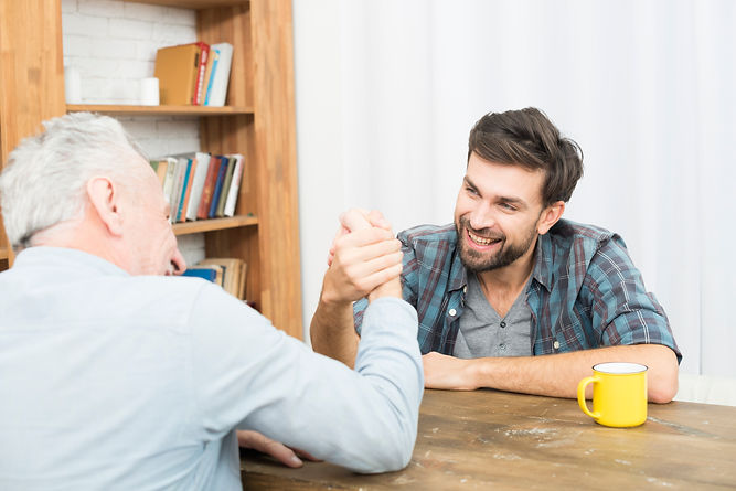 aged-man-young-happy-guy-with-hands-clasped-arm-wrestling-challenge-table-room.jpg