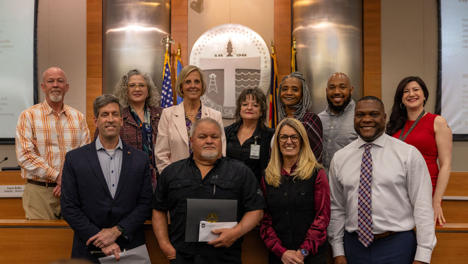 Councilor Christian Bengel joins the rest of City Council and Mayor Monroe Nichols for a group photo with a citizen receiving a proclamation at a City Council meeting.
