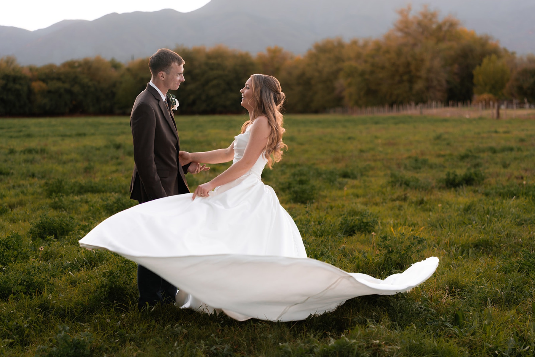 A bride and groom laughing together in a field during golden-hour wedding portraits in Arizona