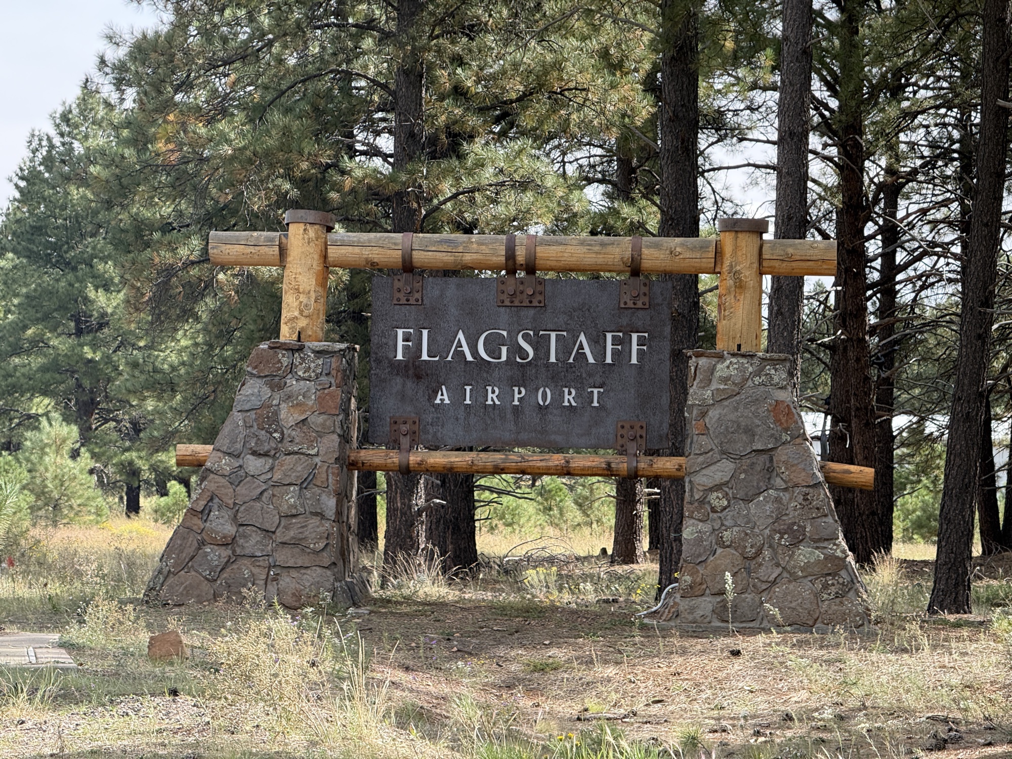 The Flagstaff Airport entrance sign surrounded by ponderosa pines in Flagstaff, Arizona.