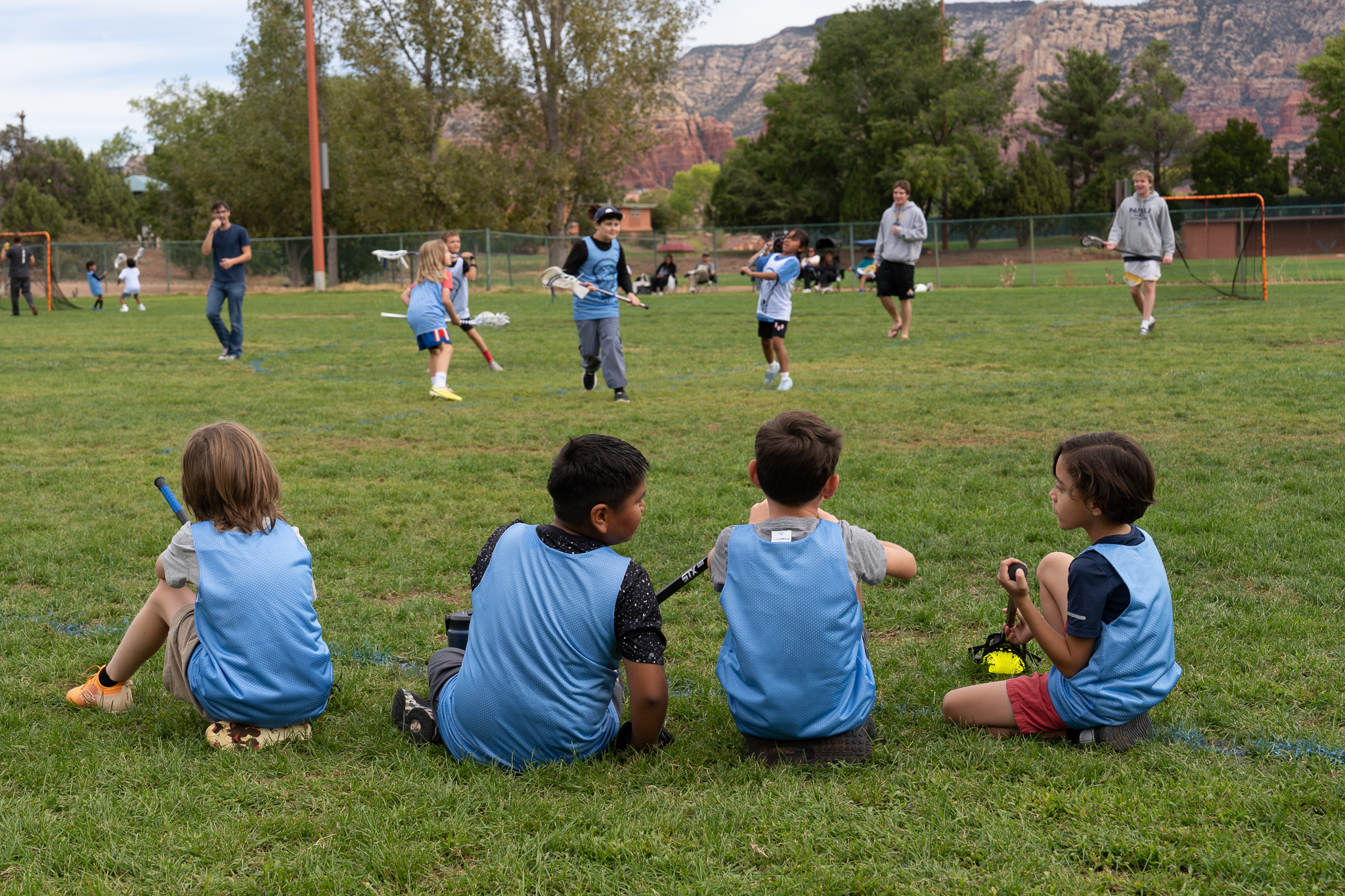 Young lacrosse players sitting together on the sideline and watching a game