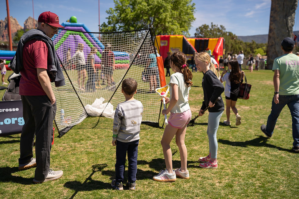 Volunteers Molly Whitehead and Lydia Nardo teach a new player how to shoot on a lacrosse goal.