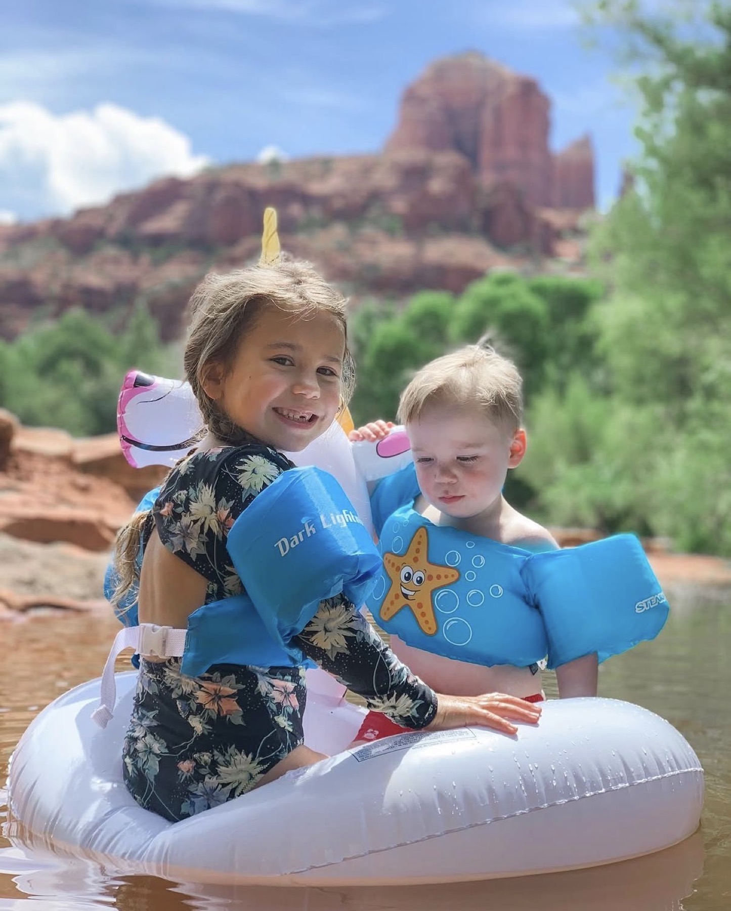 Two young children wearing flotation aids in Oak Creek at Crescent Moon Ranch in Sedona.
