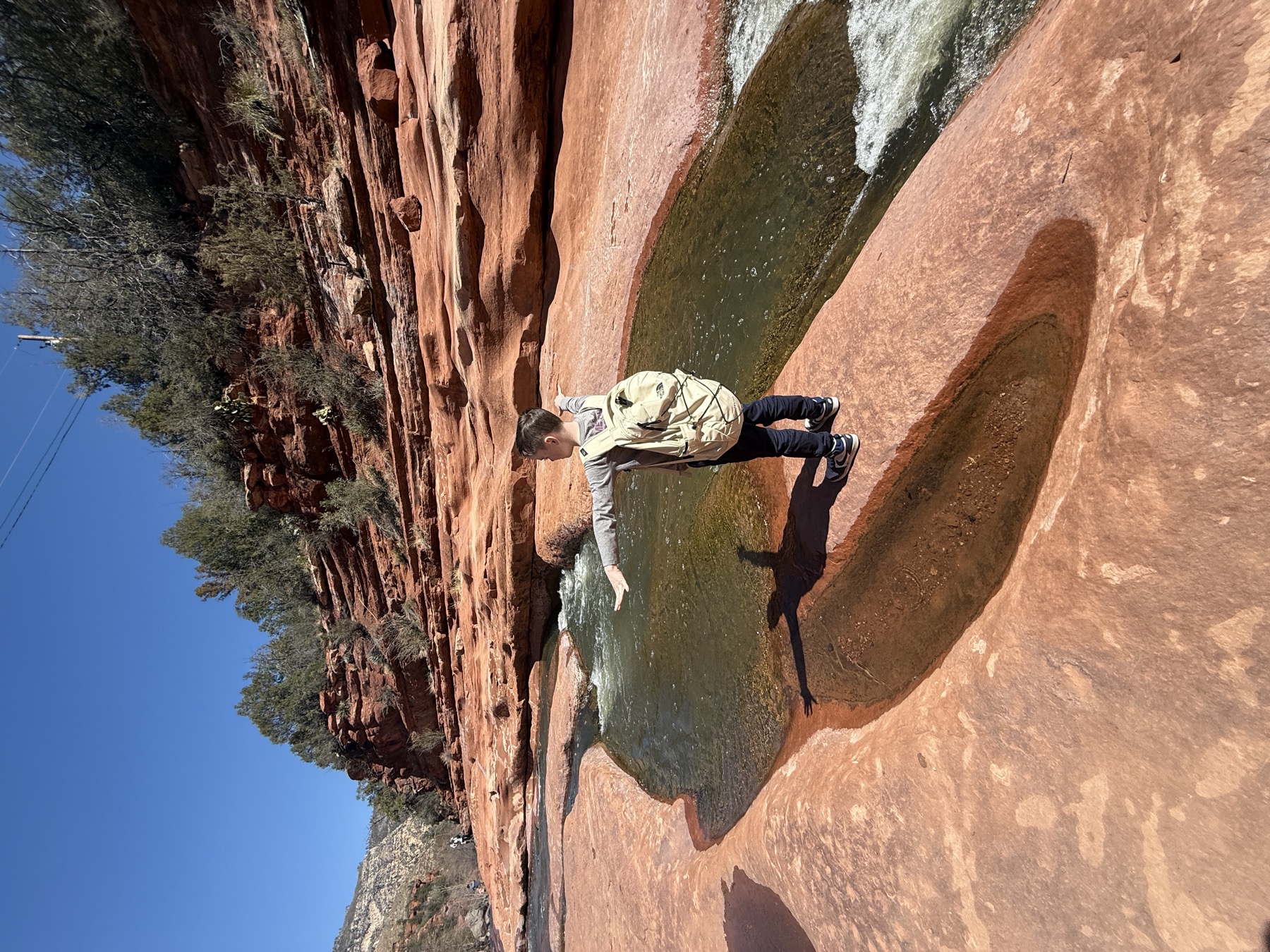 A child standing beside the natural red-rock waterslide at Slide Rock State Park near Sedona.