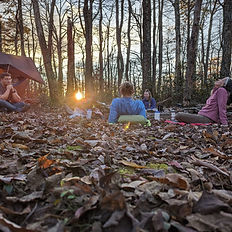 Backcountry campsite at sunset with participants resting in the woods—digital detox backpacking weekend
