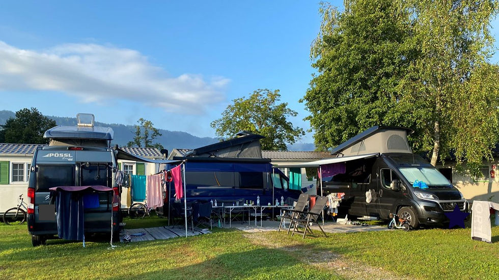 Drei Wohnmobile - Campervans stehen in einem U angeordnet auf grüner Wiese