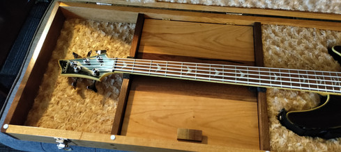 Photo of bass guitar inside case, showing the storage compartment lid and how the neck is cradled in the case