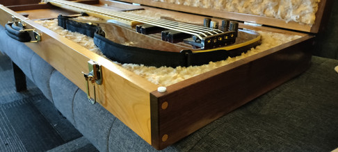 Close-up of opened bass case showing woodworking accents on corner and fuzzy fabric inside
