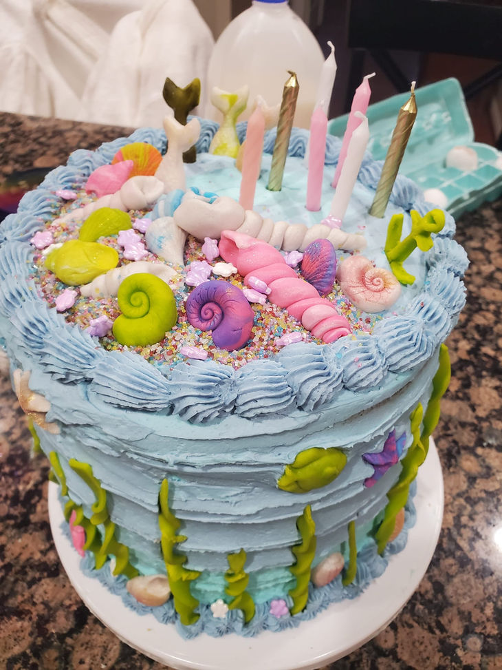 Blue mermaid themed cake with candles and ocean decorations