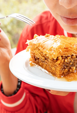 Smiling woman eats sweet puff pastry dessert with honey and walnuts - baklava.jpg