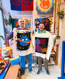 2 male friends holding their tufted carpets from a tufting workshop