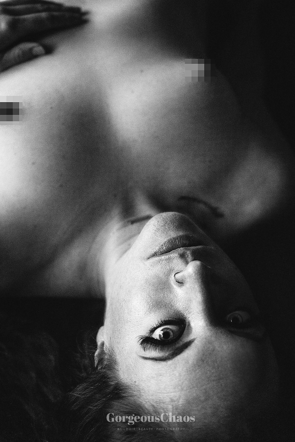 black and white nude image of women laying on back looking at camera