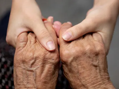 Caregiver gently holding hands of an elderly person in support and care