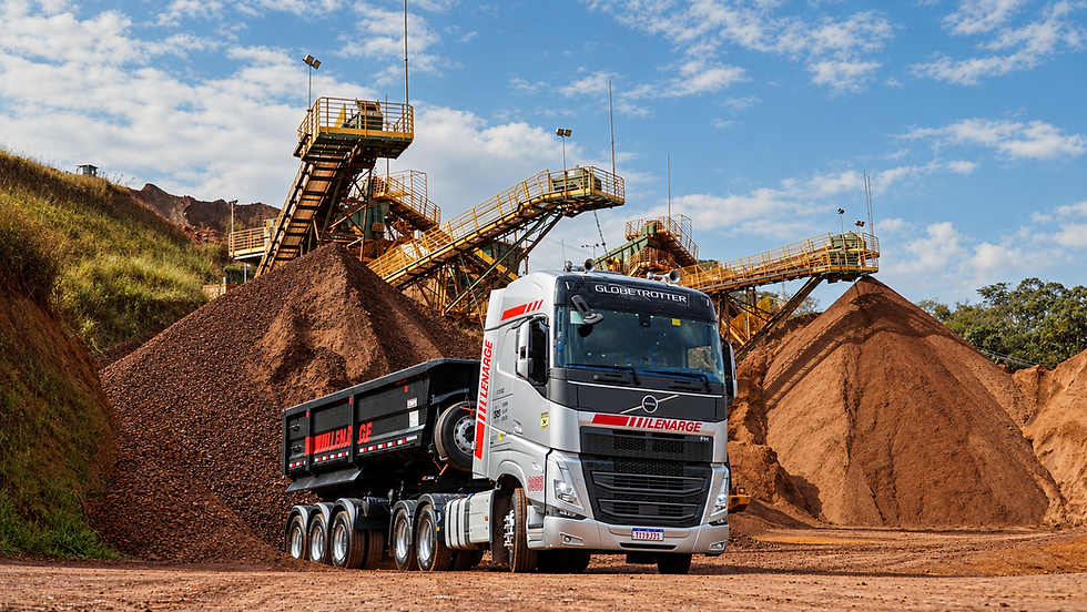 Caminhão Volvo LEnarge em mina de terra, diante de pilhas de minério e esteiras amarelas sob céu azul com nuvens. Hero Agência. Bando de Imagens Caminhão rodoviário. Fotos profissionais de caminhões. Fotos instituionais de caminhões rodoviários.