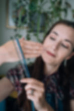 Alice, a white female knitting teacher holds 3 different strands of yarn against her hand showing different thicknesses