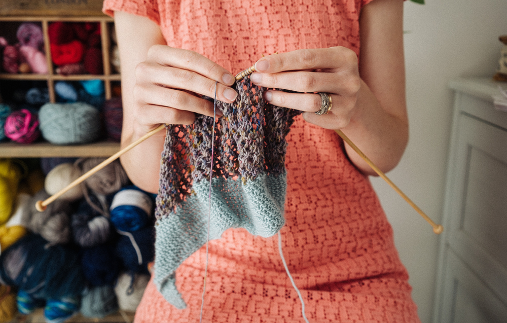 Alice, a white female knitting teacher's hands are knitting with wooden needles.