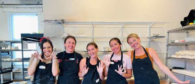 5 women in dirty aprons after throwing on the wheel