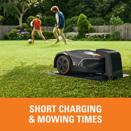 Children play soccer while robotic mower mows grass