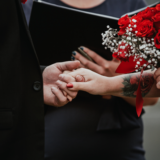 Holding hands during ceremony.  Bride with tattoos