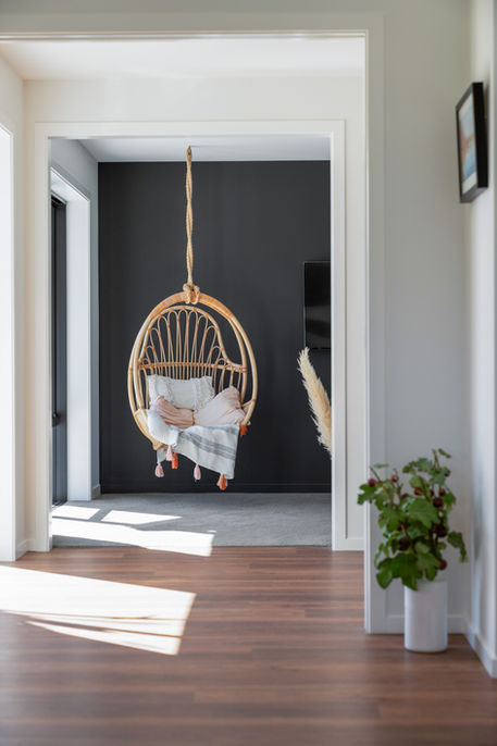 Swinging chair hanging from ceiling in TV room.