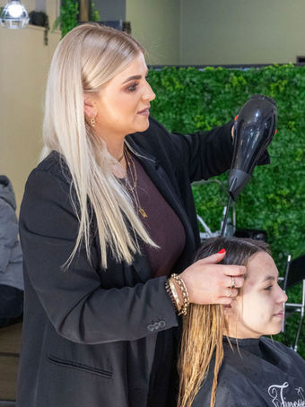 Hairdresser blow drying a woman's long hair at the salon