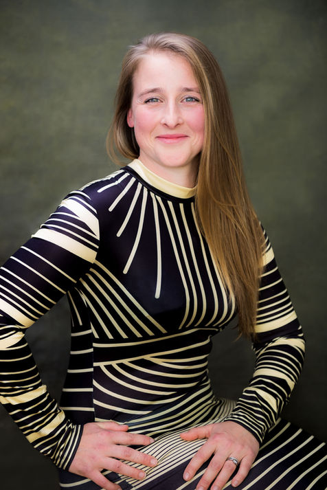 Vanity Fair styled portrait of a young woman in yellow and black dress smiling for a portrait in studio with green backdrop