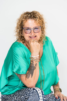 Mature blonde woman in teal satin top wearing glasses