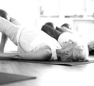 Pilates class with mixed ages practicing a gentle spinal mobility exercise