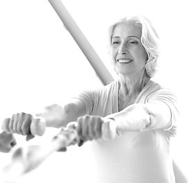 Woman in her 60s lifting handweights in a Pilates class